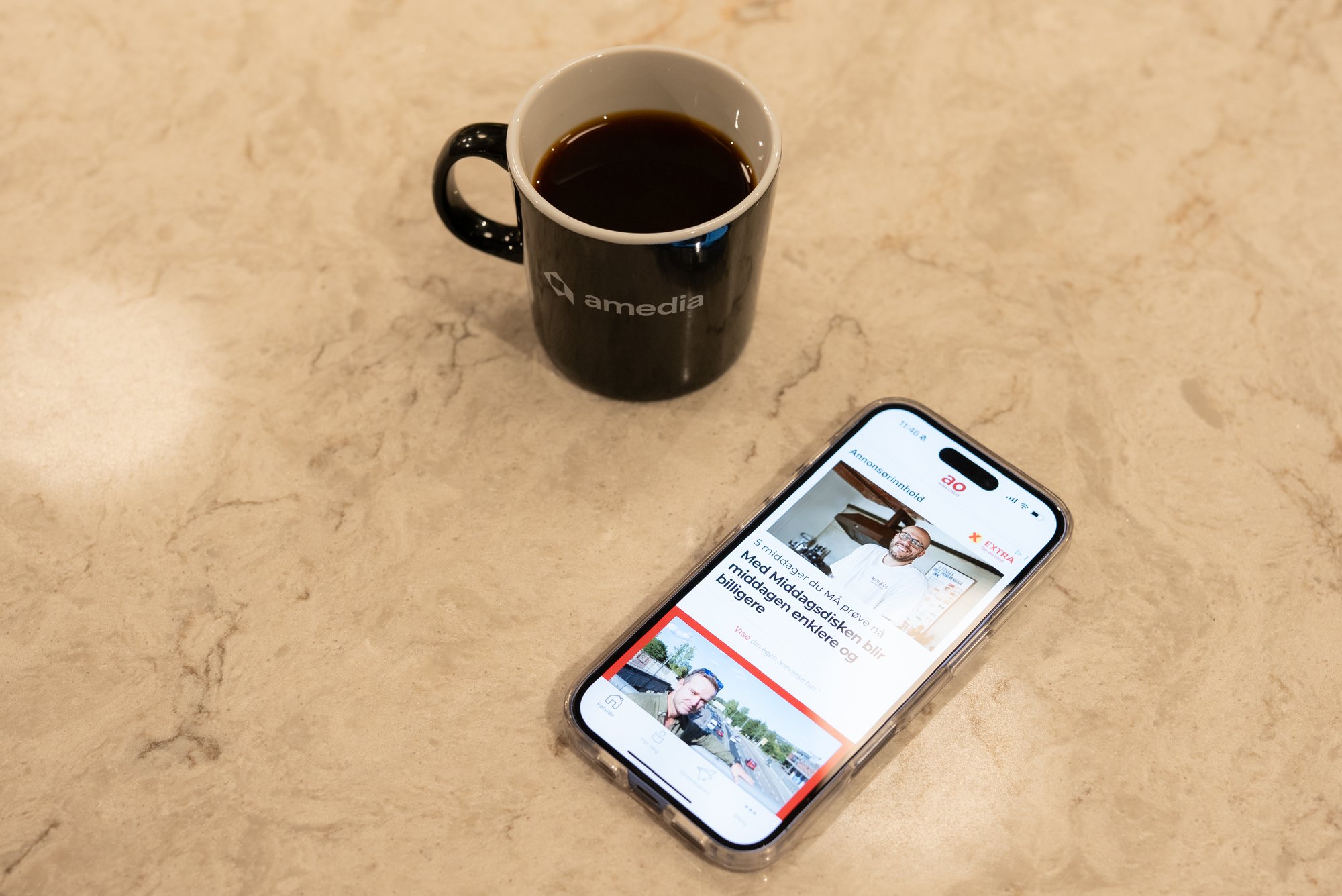 Avisa Oslo på mobiltelefon og kaffe i Amedia-koppen - Amedia Annonse
