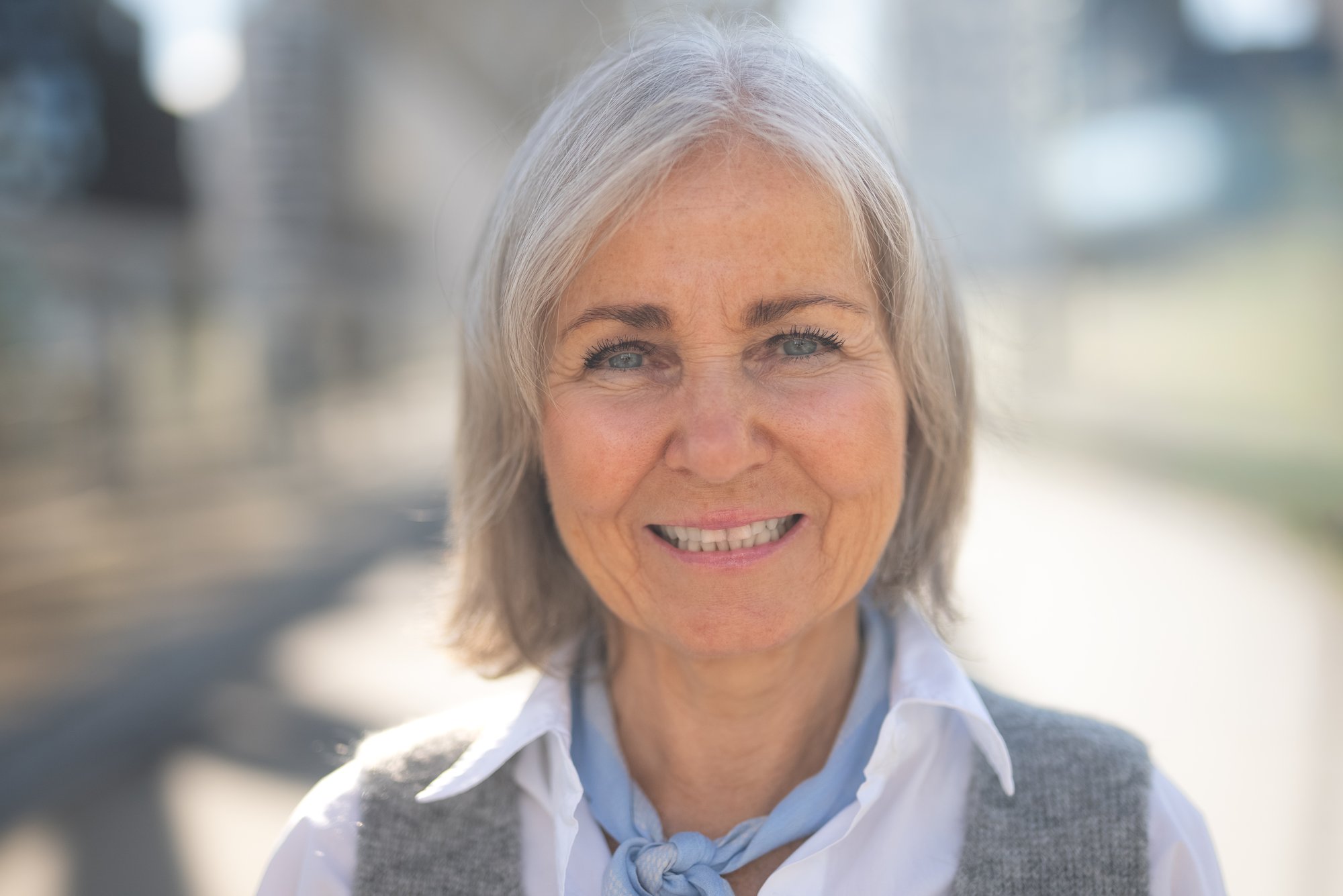 Kvinne med blått skjerf ser inn i kamera - Amedia Annonse