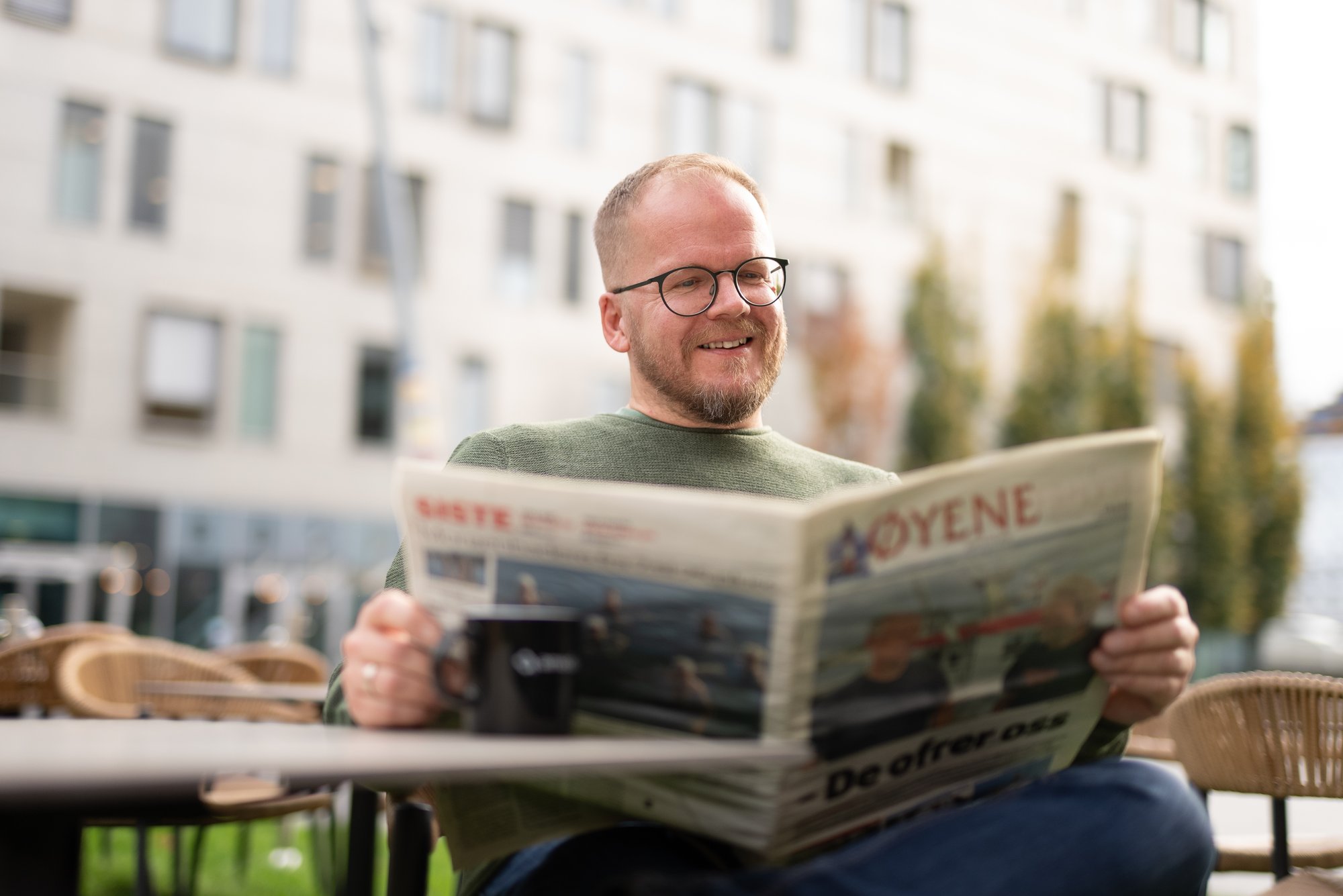 Smilende mann med briller leser Øyene - Amedia Annonse