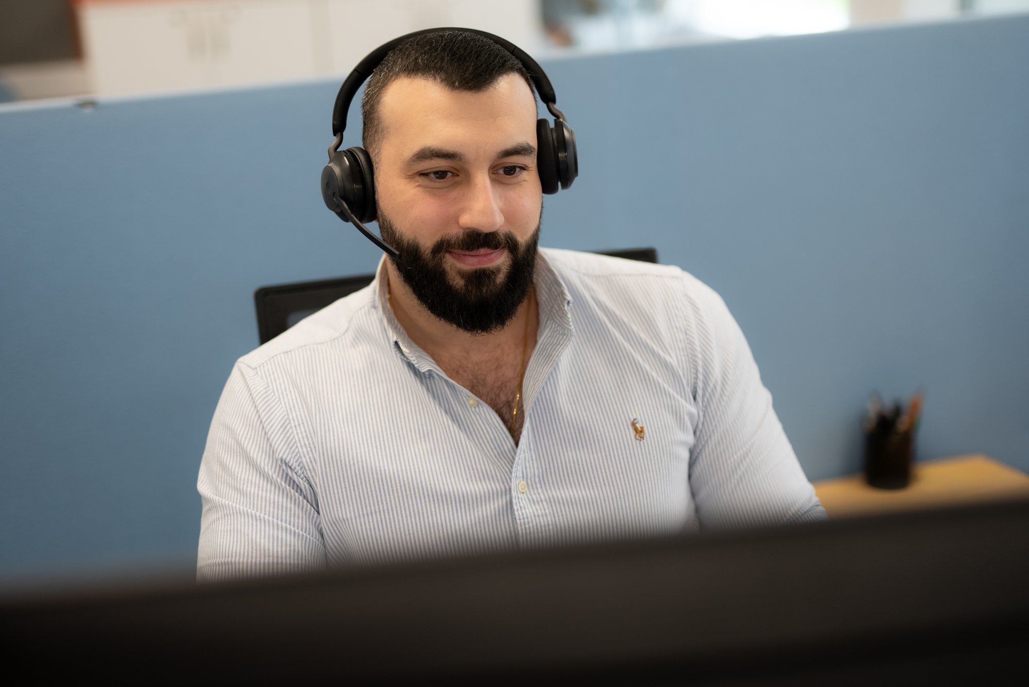 Smilende mann med headset bak PC-skjerm - Amedia Annonse