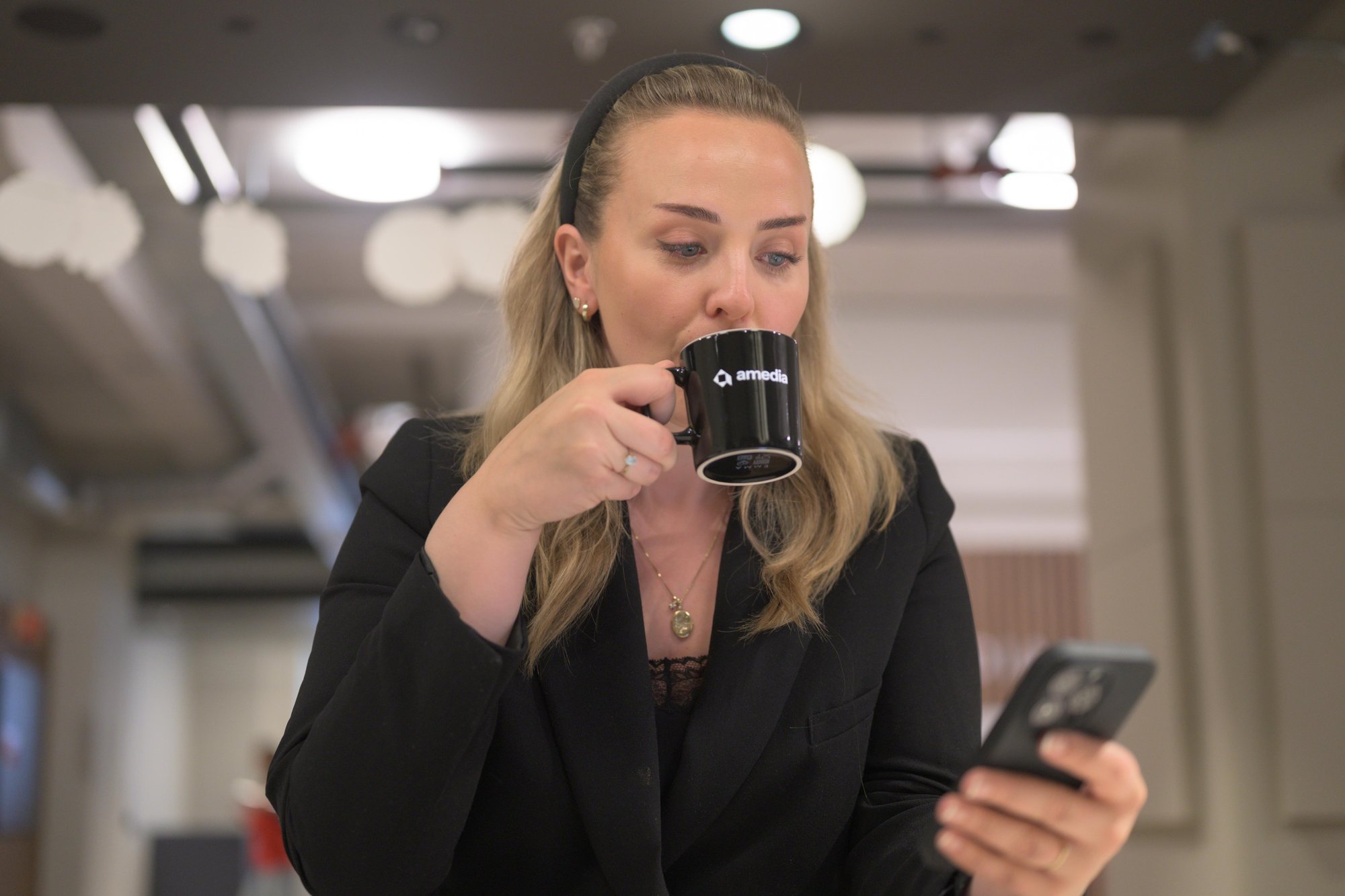 Kvinne drikker kaffe og ser på mobil
