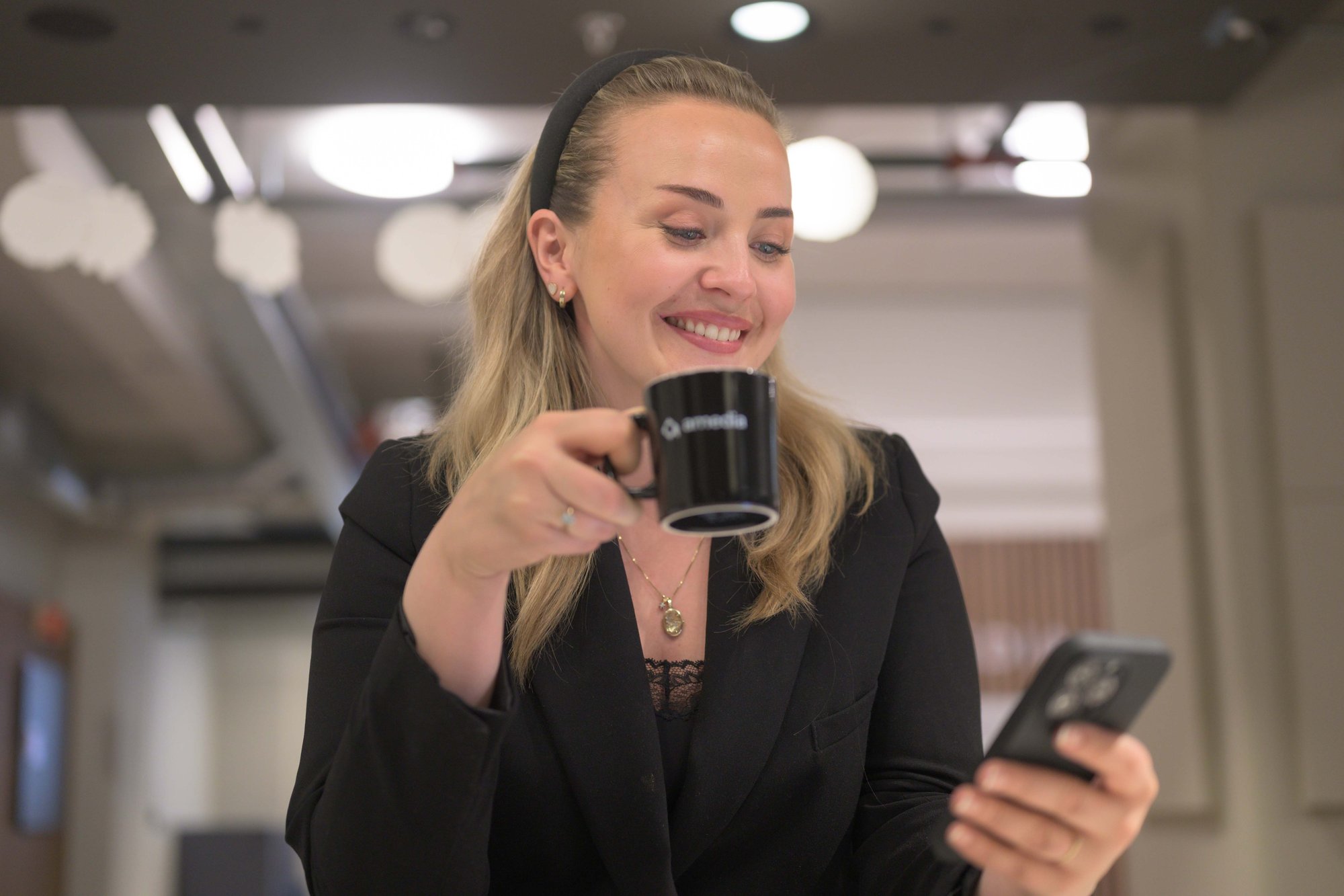 Smilende kvinne drikker kaffe og ser på mobil