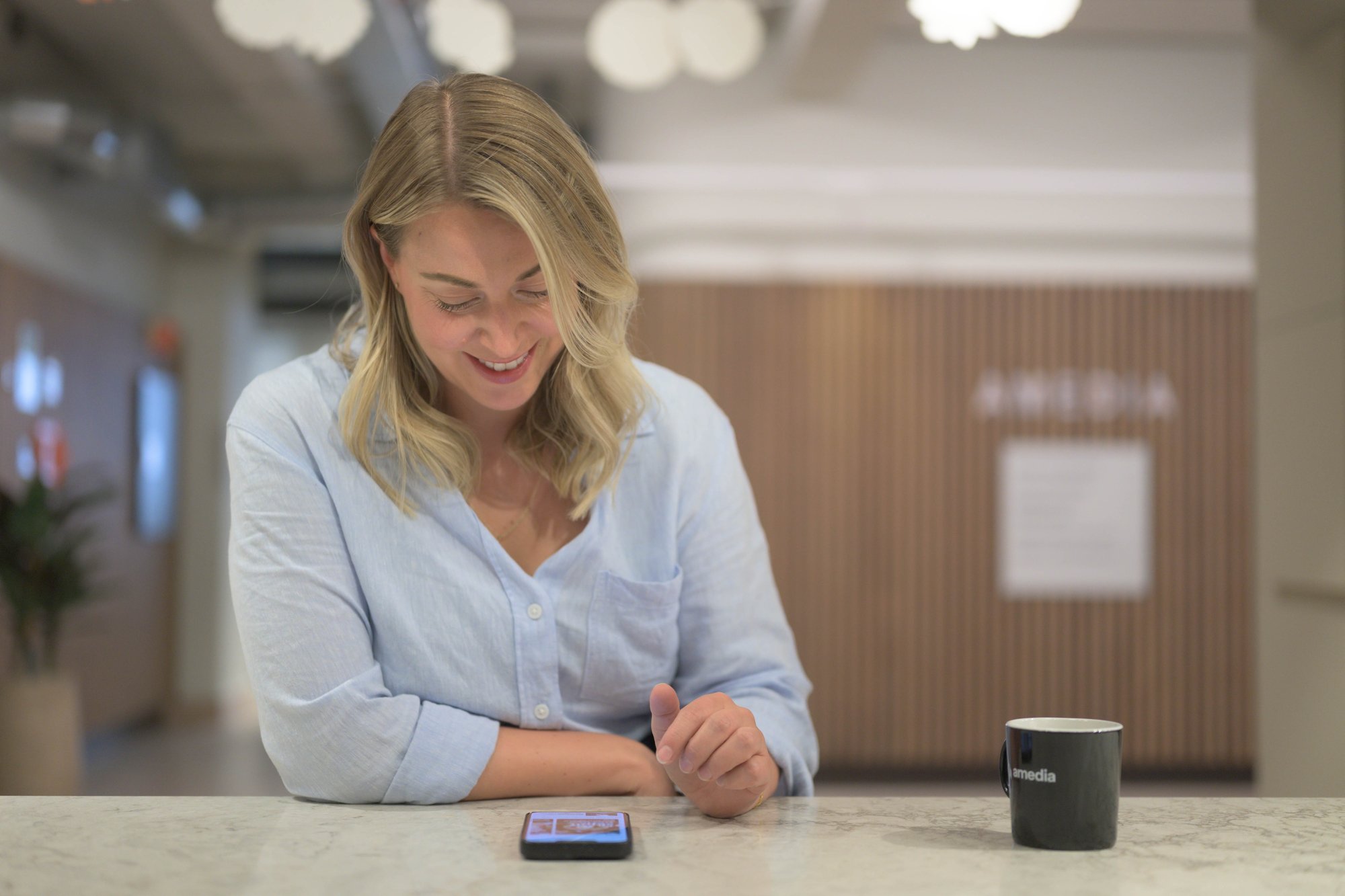 Smilende kvinne ser ned på mobilen