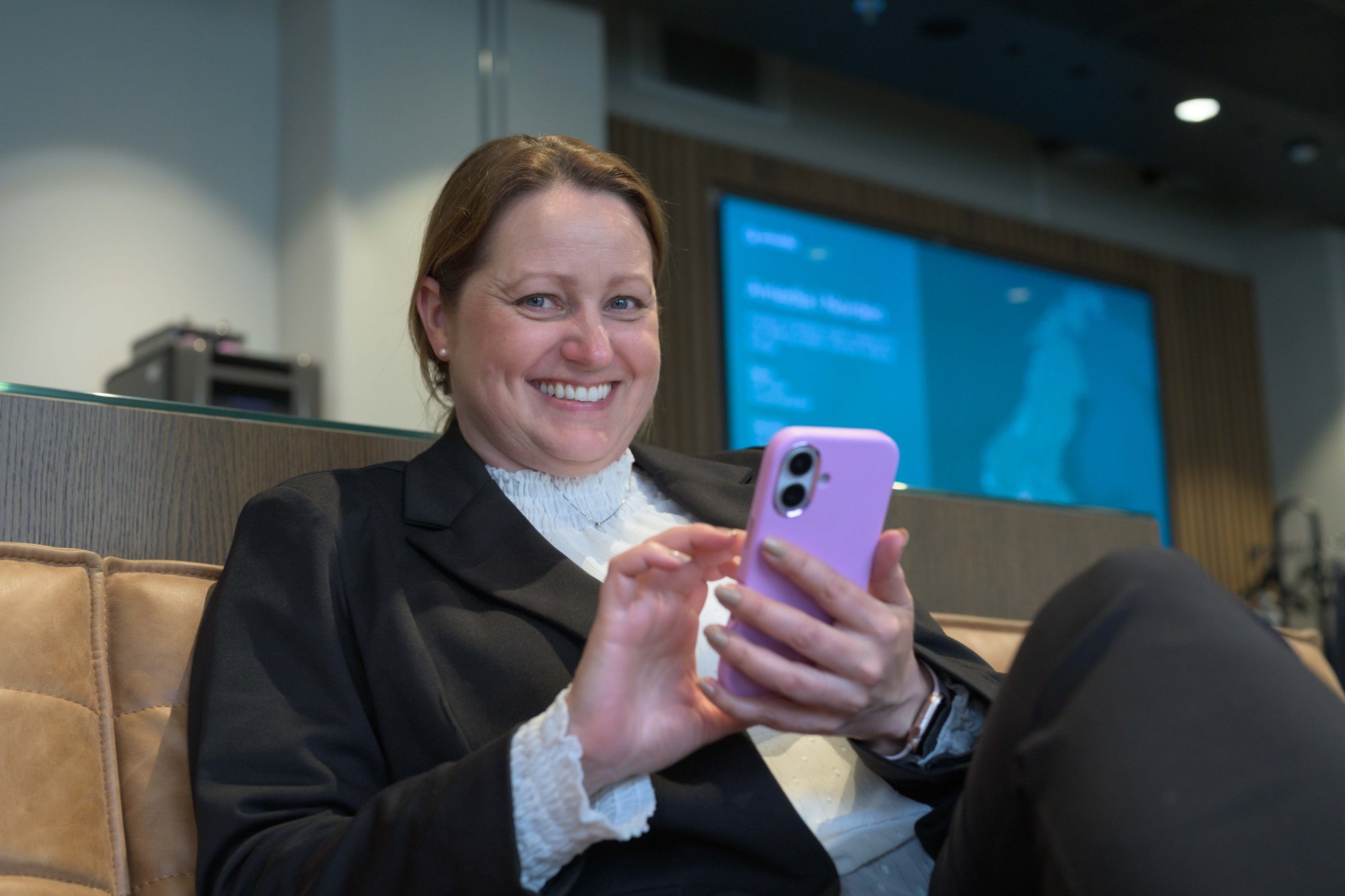 Smilende kvinne med rosa mobiltelefon