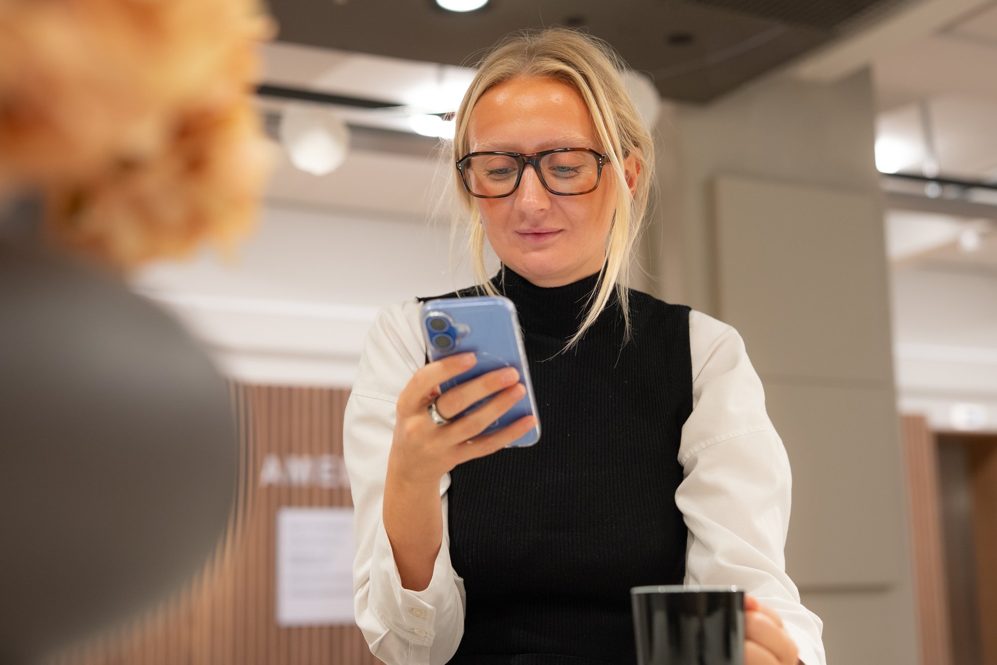 Ung kvinne med briller ser på mobiltelefon - Amedia Annonse