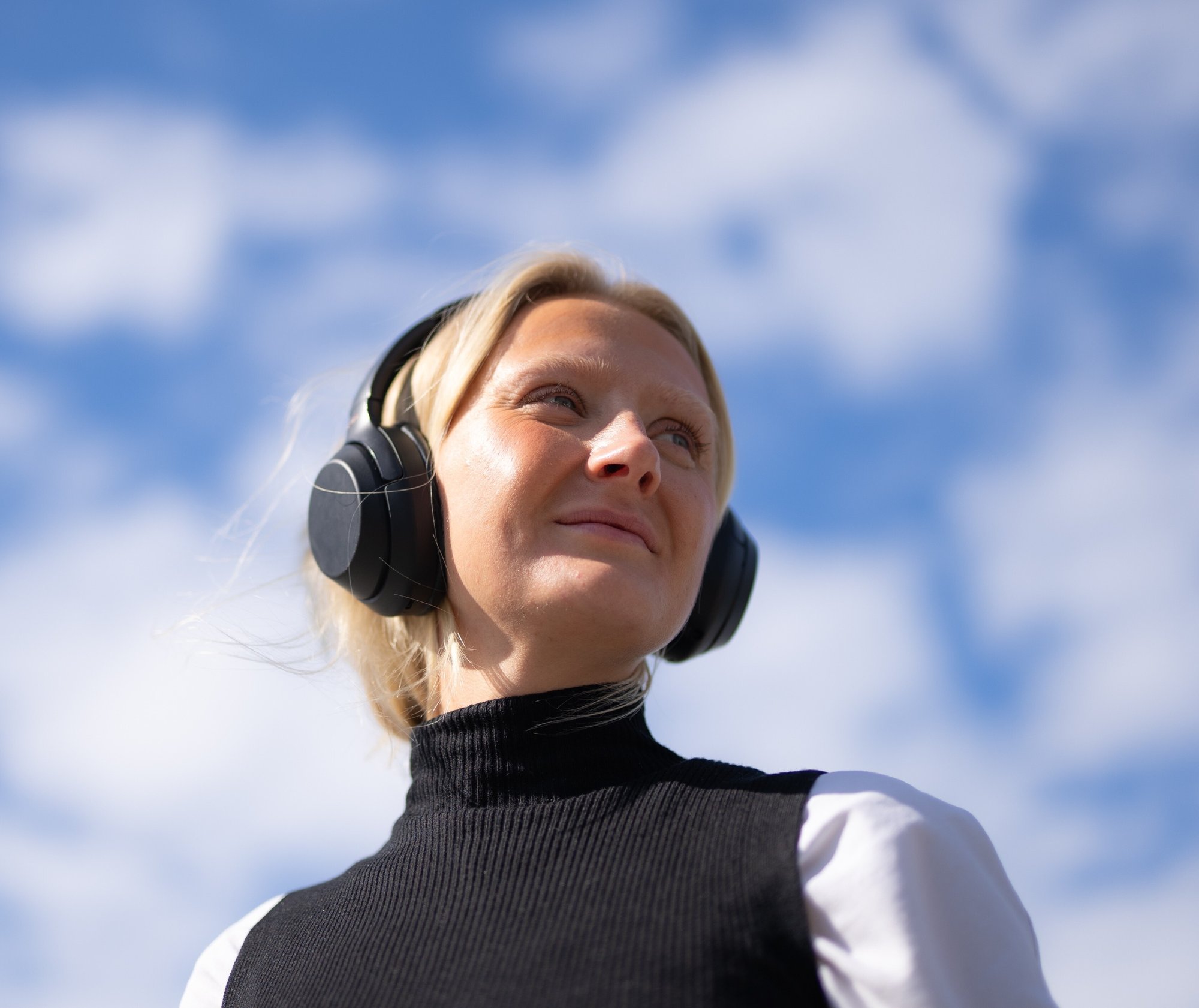 imgi_2_Ung kvinne med headset og blå himmel i bakgrunnen - Amedia Annonse